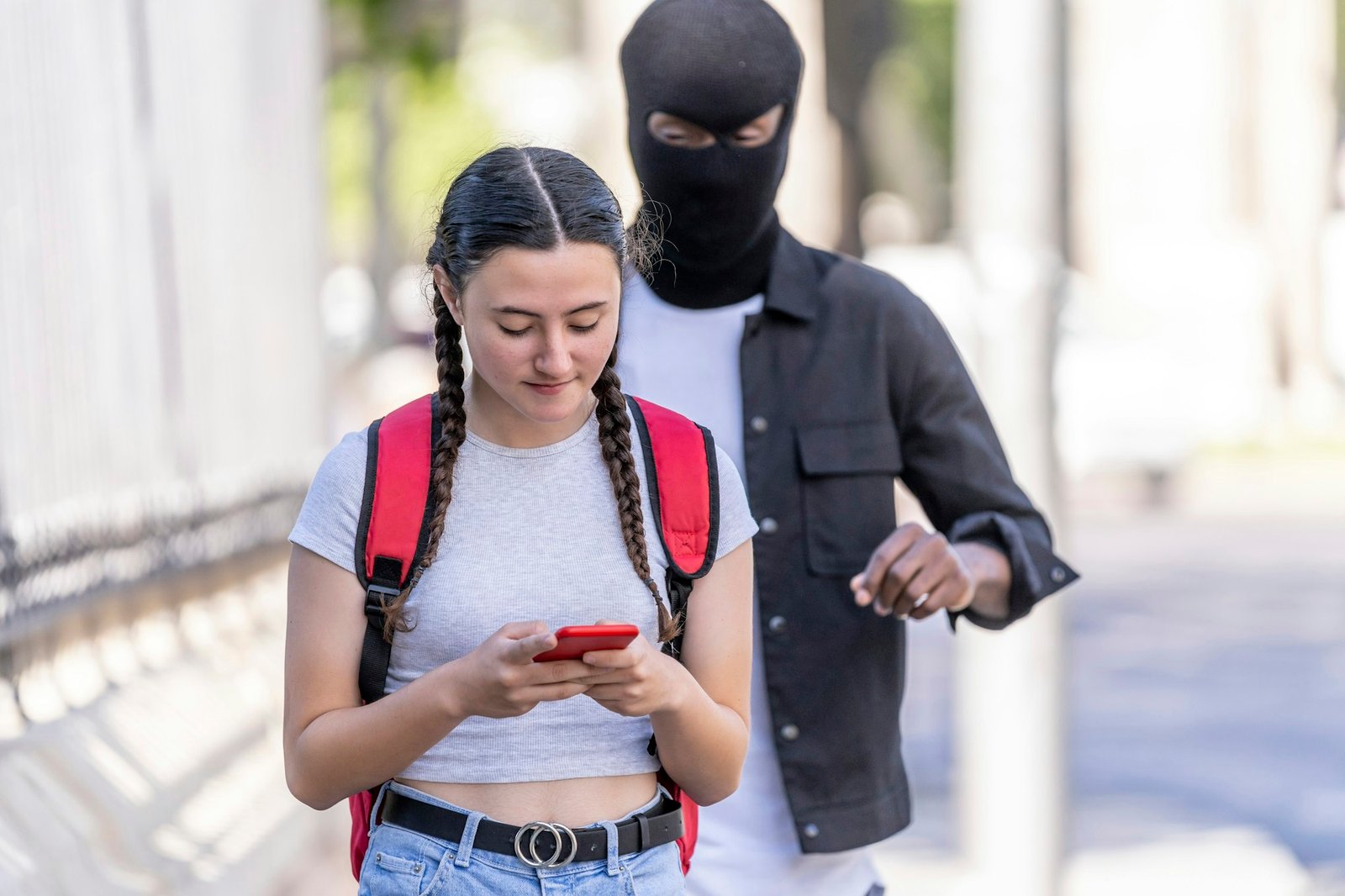 Man with balaclava on his head stealing cell phone from young woman